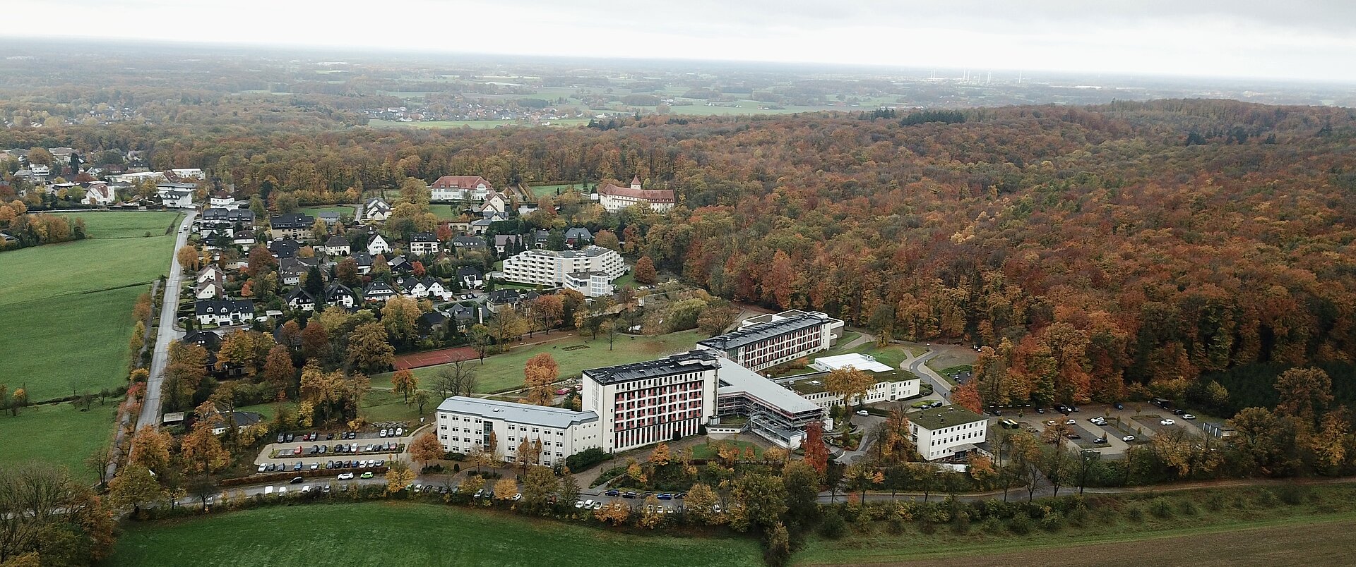 Drohnenaufnahme auf einen Gebäudekomplex mit Wald da neben.