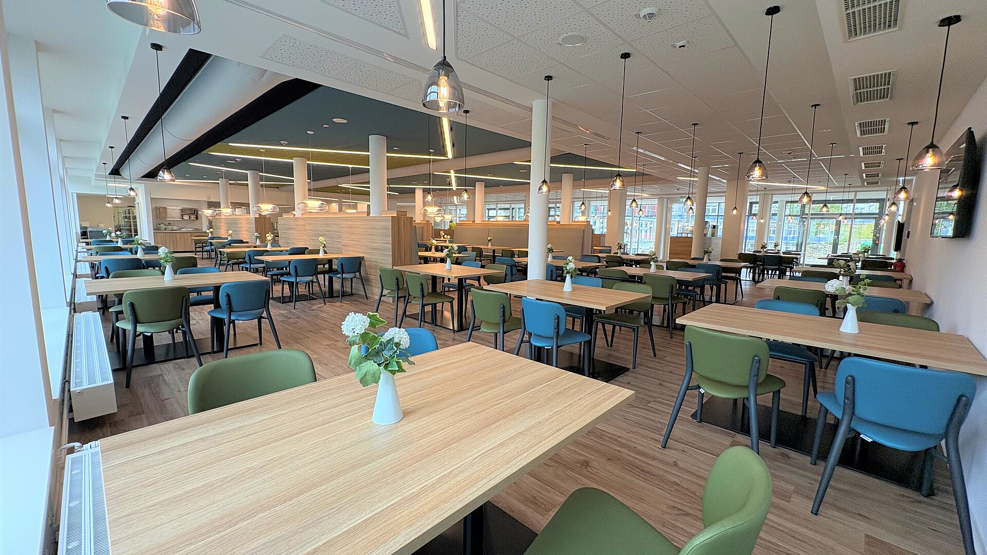Ein geräumiges Restaurant mit vielen Tischen und Stühlen, wo die Gäste ihre Mahlzeiten genießen können.