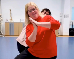 Zwei Frauen machen grinsend Yogaübungen im Stehen.